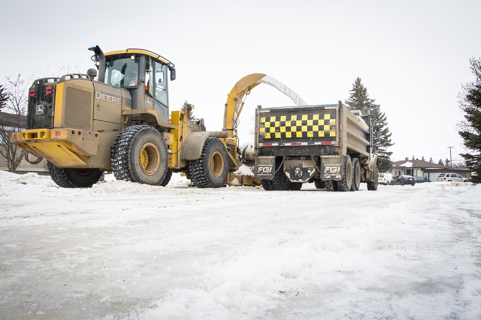 grader putting snow in dump truck